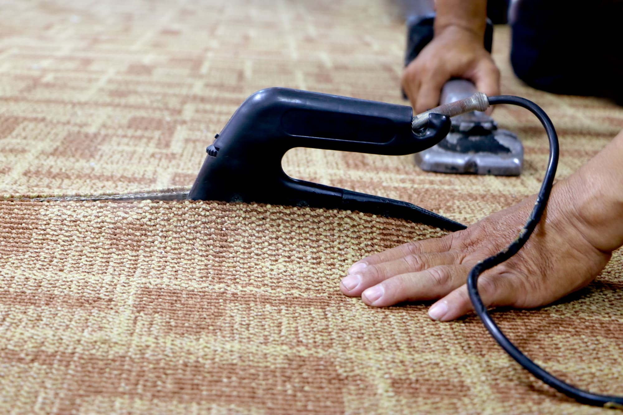 close-up of a craftman connecting the wall to wall carpet with heat bond iron.